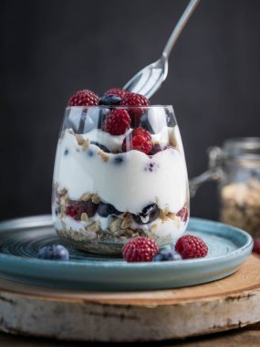 Böğürtlenli ve yoğurtlu granola parfe. Siyah arka planda granola, ahududu ve yaban mersinli parfe. Bardakta granola. . 