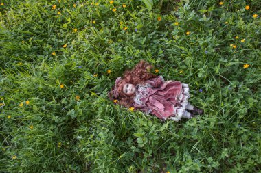 Old doll lost in the grass clipart