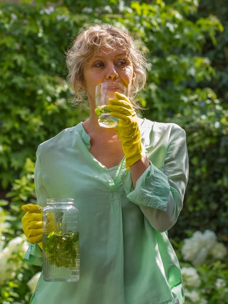 Привлекательная женщина во время паузы пьет воду с мятой и лемом — стоковое фото