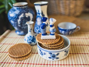 Delfts blue decorative crockery set on the table with traditional Dutch cookies stroopwafels, clipart