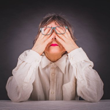 Yorgun kadın, yorgun gözlerini elleriyle ovalıyor.