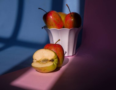 Pembe ve mavi arka planda bir elmanın kabın içindeki fotoğrafı