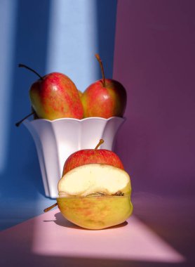 Pembe ve mavi arka planda bir elmanın kabın içindeki fotoğrafı