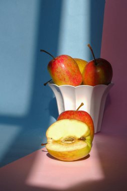 Pembe ve mavi arka planda bir elmanın kabın içindeki fotoğrafı