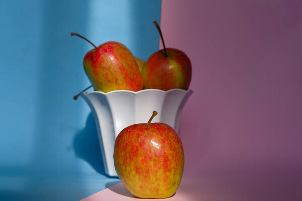Фото яблока в контейнере на розовом и синем фоне