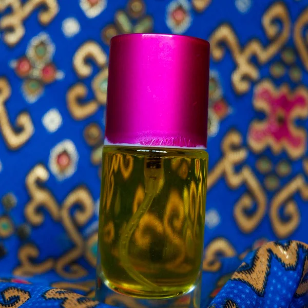 蓝色蜡染背景上带有黄色香水的香水瓶 — 图库照片