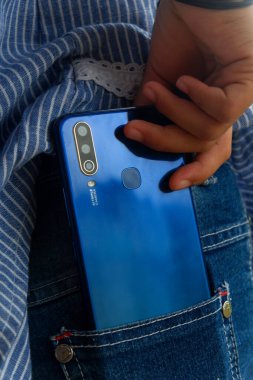 Küçük bir Asyalı çocuğun elinde mavi bir akıllı telefon tutarken fotoğrafı.