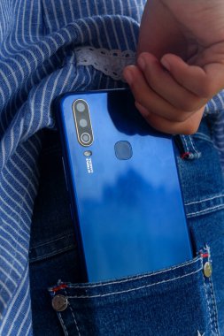 Küçük bir Asyalı çocuğun elinde mavi bir akıllı telefon tutarken fotoğrafı.
