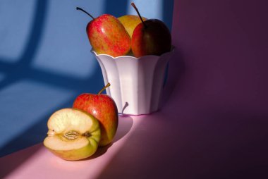 Pembe ve mavi arka planda bir elmanın kabın içindeki fotoğrafı