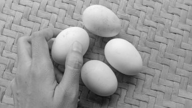 Örgü bambu arka planında siyah beyaz temalı 4 tavuk yumurtası.