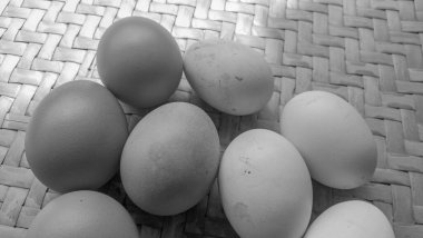 Örgü bambu arka planında siyah beyaz temalı 4 tavuk yumurtası.