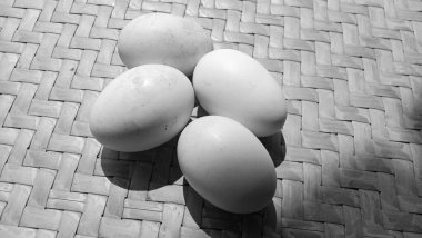 Örgü bambu arka planında siyah beyaz temalı 4 tavuk yumurtası.