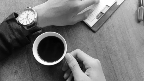 木製のテーブルの上で黒いコーヒーを楽しんでいる人の写真 — ストック写真