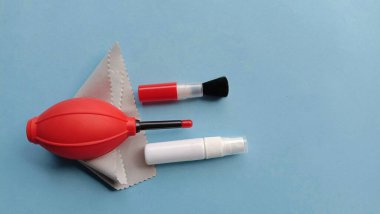 Hava üfleyici, fırça, mikrofiber bez, mavi arka planda su spreyi gibi kamera temizleme malzemelerinin fotoğrafı