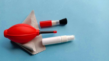 Hava üfleyici, fırça, mikrofiber bez, mavi arka planda su spreyi gibi kamera temizleme malzemelerinin fotoğrafı