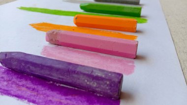 Kağıdın kenarında turuncu ve sarı renkli boya kalemi olan bir kağıt.