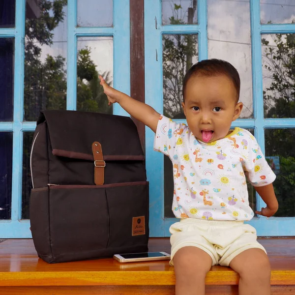 Foto Niño Sentado Una Mesa Con Una Bolsa Negra Lado —  Fotos de Stock