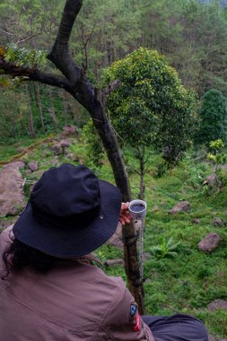 July 13, 2020, a man sits on a hill with a beautiful view, Wadaslintang, Indonesia