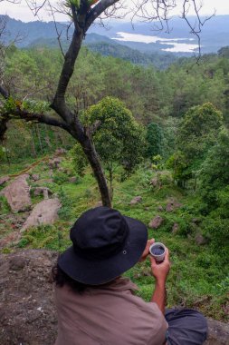 July 13, 2020, a man sits on a hill with a beautiful view, Wadaslintang, Indonesia
