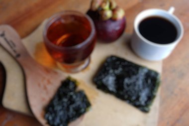 Ahşap arka planda hafif deniz yosunu ve kahvenin bulanık fotoğrafı