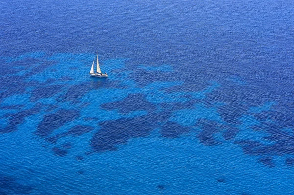 A boat with a white sail in a blue sea — Stock Photo, Image