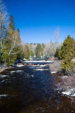 Karla kaplı ağaçlar ve hızlı nehirlerle kaplı kış manzarası