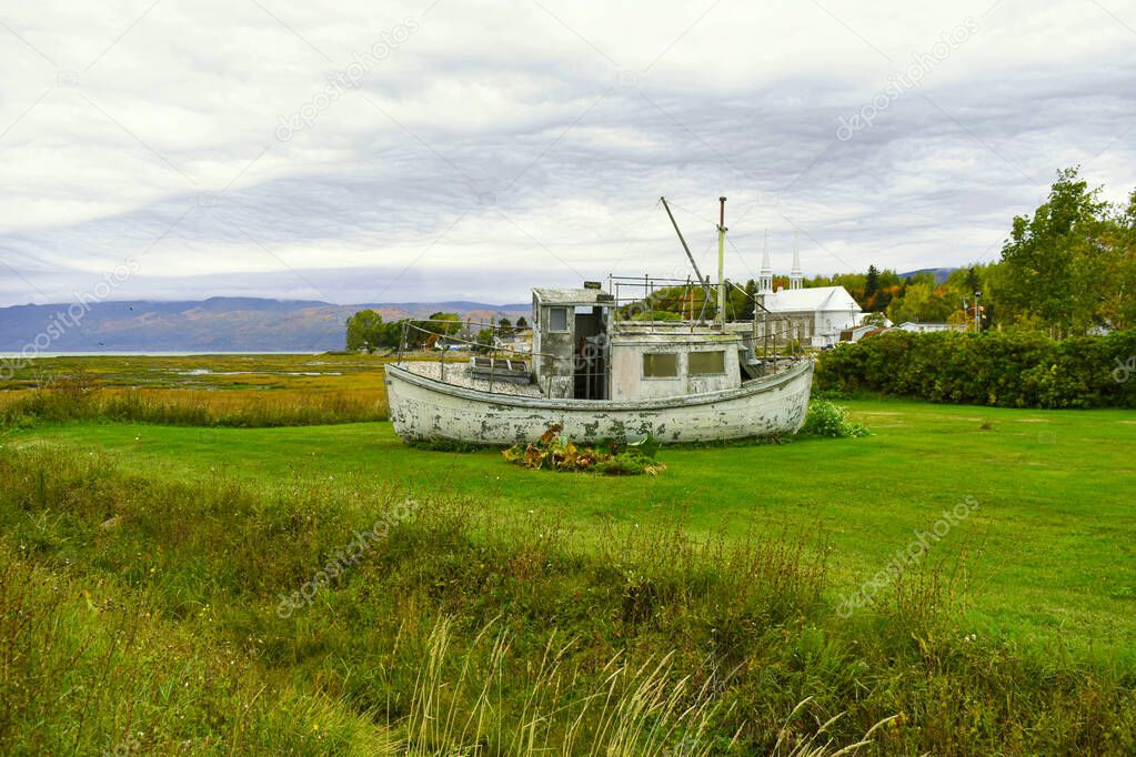 pretty little fishing boat in a field near the St. Lawrence River on a cloudy autumn day