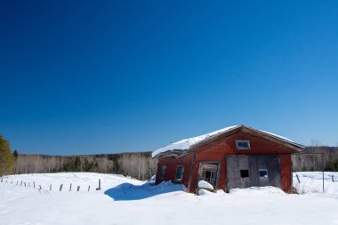 Karlı kış manzarasında terk edilmiş eski bir ahır.