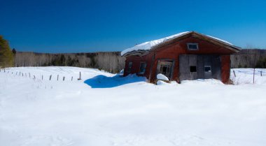 Karlı kış manzarasında terk edilmiş eski bir ahır.