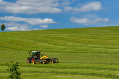 Çekici doğa arka planında tarlayı sürüyor.