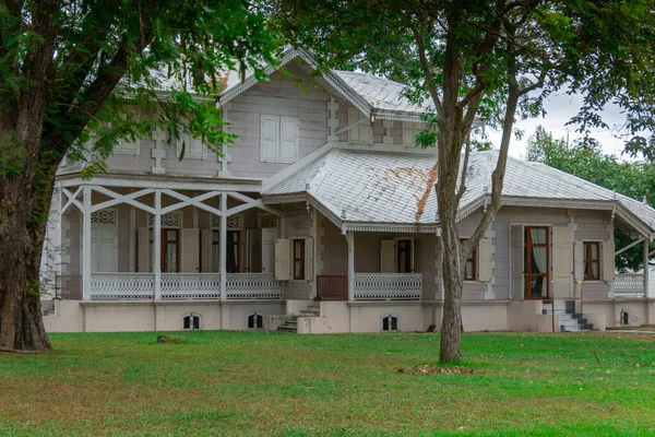 Yeşil ağaçlarla çevrili tarihi bir ev.