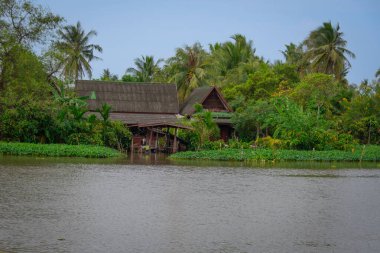 Nehir kenarındaki geleneksel ev yeşilliklerle çevrili.