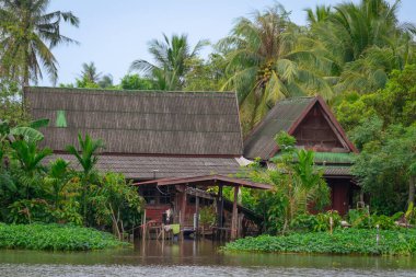 Nehir kenarındaki geleneksel ev yeşilliklerle çevrili.