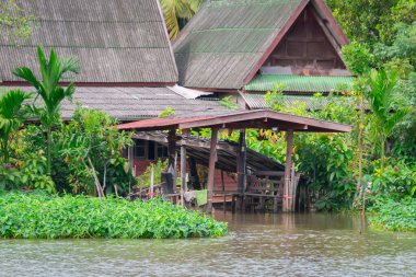 Nehir kenarındaki geleneksel ev yeşilliklerle çevrili.