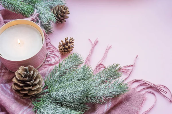 Aromatik yanan mum, köknar dalları, külahlar ve pembe arka planda fotokopi alanı olan bir ekose. Noel arkaplanı.