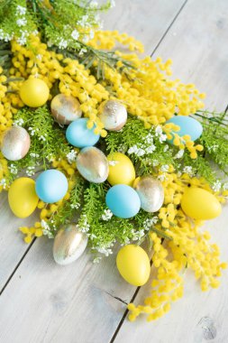 Mimoza dalları üzerinde sarı, mavi ve altın yumurtalar. Paskalya 'da hayat.