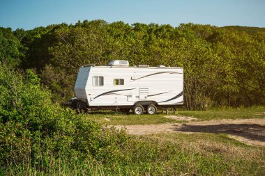 Seyahat karavanı şafak vakti ormanın yakınındaki çayırda duruyor. Seyahat karavanı karavanın park yerinde..