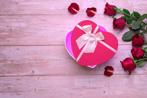 Open heart shaped box lovers\' gifts on wooden surface, roses, petals. Valentine\'s day 14 february or romantic evening invitation,  postcard, poster, decoration.