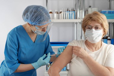 Yetişkin yaşlı bayana aşıyı enjekte eden profesyonel bir kadın. Açık hava hastanesi sağlık durumu