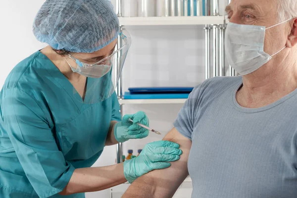 Yetişkin bir adama aşıyı enjekte eden profesyonel bir kadın. Açık hava hastanesi sağlık durumu