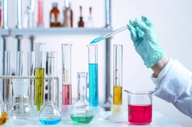 Eldivenle pipeti sıvıyla manipüle etmek. Laboratuvarda kimyasal yeni teknolojik deneyler