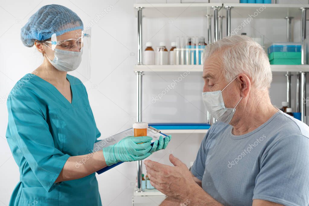 Female nurse holding a clipboard folder, giving prescription drug orange pill jar  to adult senior man. Doctor's appointment hospital healthcare case