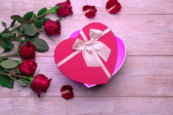 Open heart shaped box lovers' gifts on wooden surface, roses, petals. Valentine's day 14 february or romantic evening invitation,  postcard, poster, decoration.