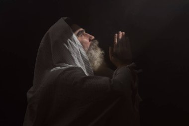 Yukarıdan gelen koyu dumanlı arka plan ışık huzmesinin içinde son sınıf öğrencisi. Dua jesti.