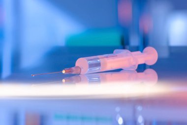 Sağlık ve tıbbi konsept - hastanede şırınga ve ampul ilaçlar. Yansımalı cam masa üstü. Mavi ultraviyole ışıklandırma kuartzizasyonu steril odası. Görüntüyü kapat