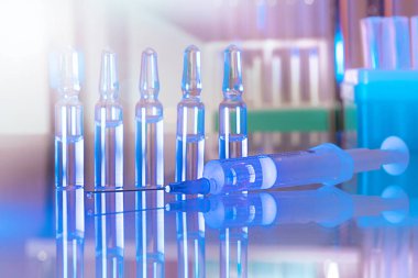 Sağlık ve tıbbi konsept - hastanede şırınga ve ampul ilaçlar. Yansımalı cam masa üstü. Mavi ultraviyole ışıklandırma kuartzizasyonu steril odası. Görüntüyü kapat