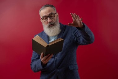 Senior charismatic man with a gray beard in a light shirt in a dark casual jacket holding a book and gestures, reciting poems, essays, novels clipart