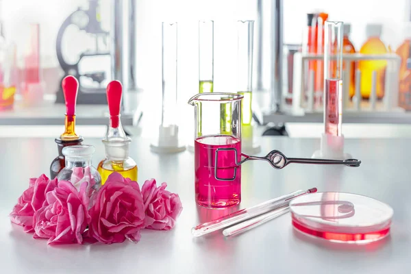 Fragment of a desktop in a perfume laboratory. Flowers, petri dish, test tubes, pipettes.