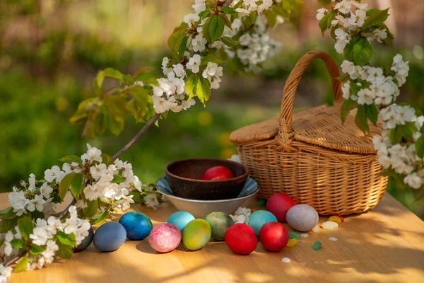 Easter brunch outdoor. Colorful eggs, bean-shaped lollipops, blossoming cherry branches on a wooden table