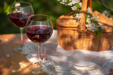 Baharda bahçede şarap tatma partisi. Güzel bir ilkbahar gününde, tahta bir masada, uzun, saplı bardaklarla, kırmızı şarapla dolu bir hayat. Kiraz çiçekleriyle çiçek açan dallar. Seçili odak